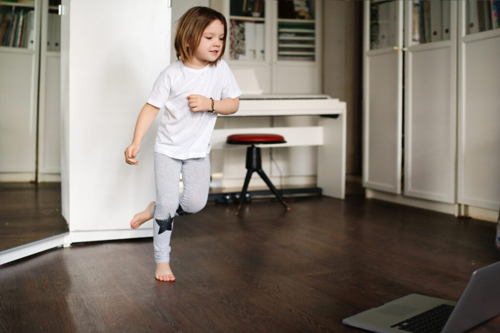 child girl is engaged in dancing, aerobics in online video chat with laptop, girl dancing in front of laptop camera.concept of remote sports and dancing in children, children's sports sections online.